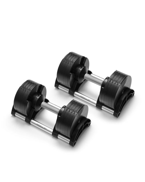 NÜOBELL 550 adjustable dumbbell set positioned at three-quarter angle against white background, highlighting the textured grip surface on aluminum handles, layered weight plate construction with visible adjustment markings, and curved storage cradle bases that support the dumbbells during rest periods.